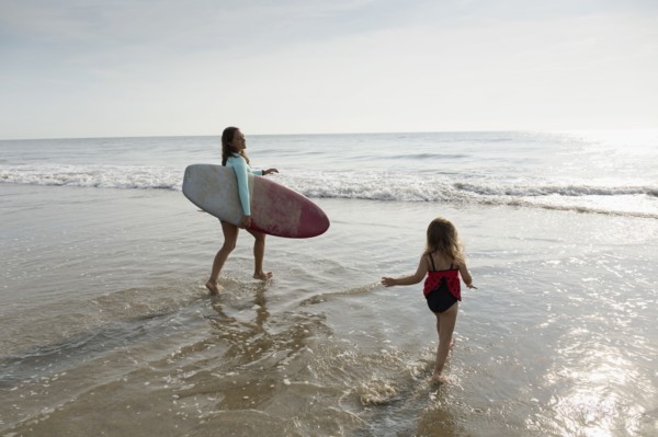 Mother and daughter playing in waves on beach