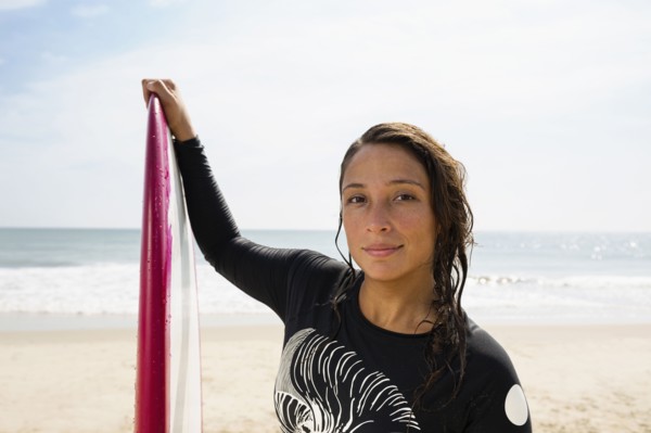 Hispanic surfer holding surfboard on beach