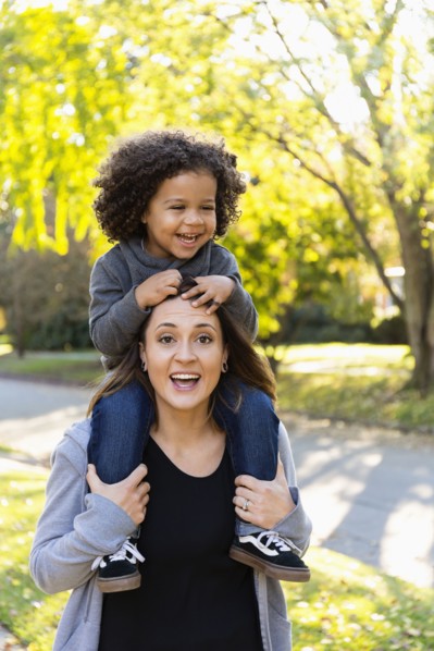 Mother carrying son on shoulders outdoors