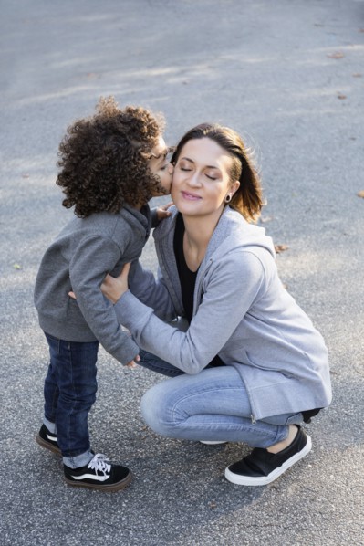 Boy kissing cheek of mother outdoors