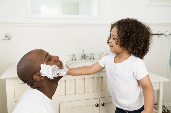 Boy helping father shave in bathroom