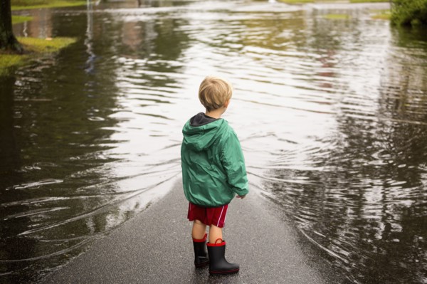 Caucasian boy wearing puddles near flood