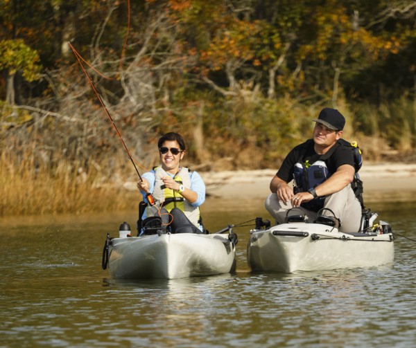 Couple fly fishing in kayaks on river