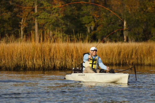 Caucasian man fly fishing in kayak on river