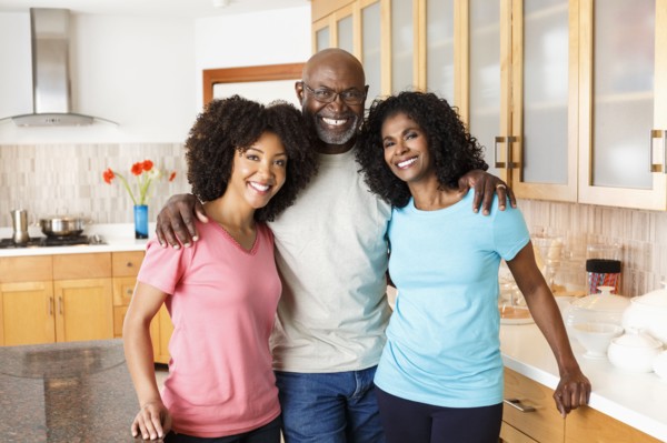 Black family hugging in kitchen