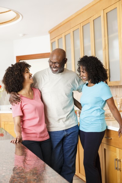 Black family hugging in kitchen