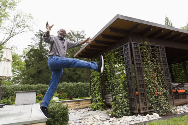 Black man jumping mid-air from bench in garden