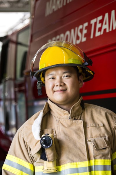 Smiling Chinese fireman standing near fire truck