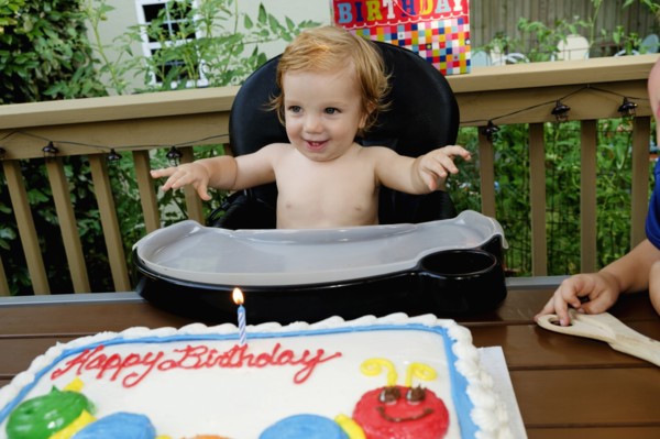 Caucasian baby boy in high chair near birthday cake