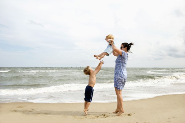Caucasian mother and sons playing at beach