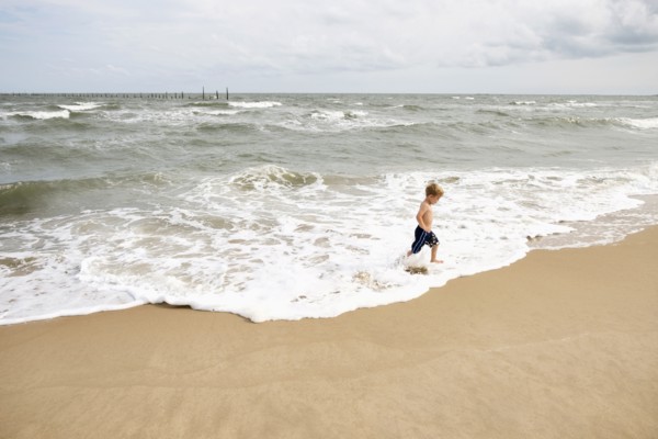 Caucasian boy running in waves at beach
