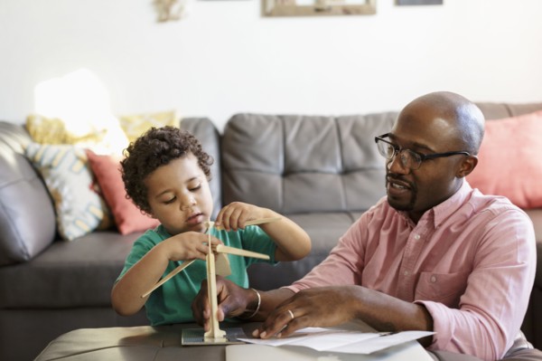 Father and son building model windmill in livingroom