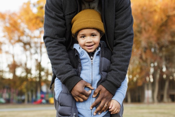 Father leaning over son in park