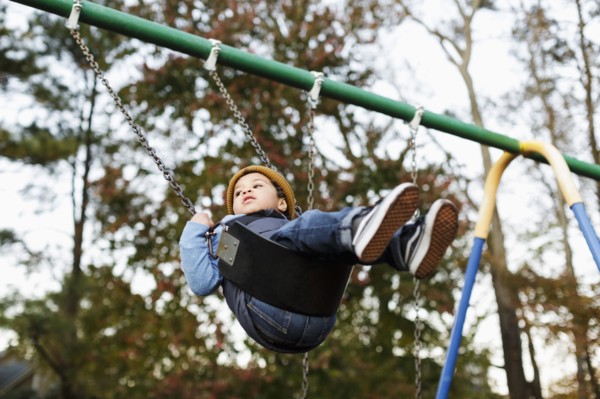 Mixed Race boy on playground swing