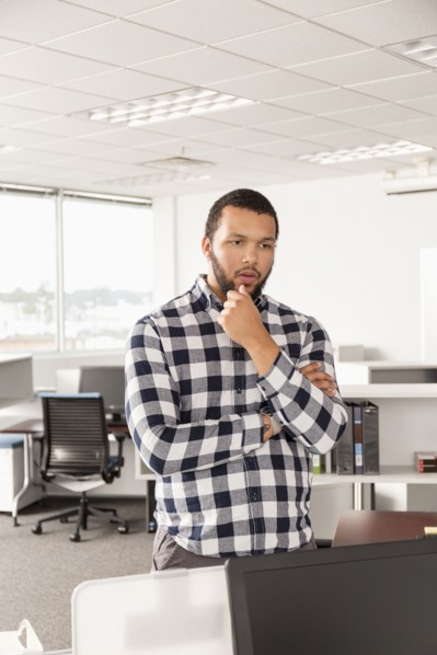 Pensive Mixed Race man standing in office