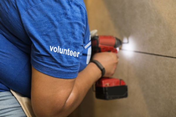 Volunteer black woman drilling wall