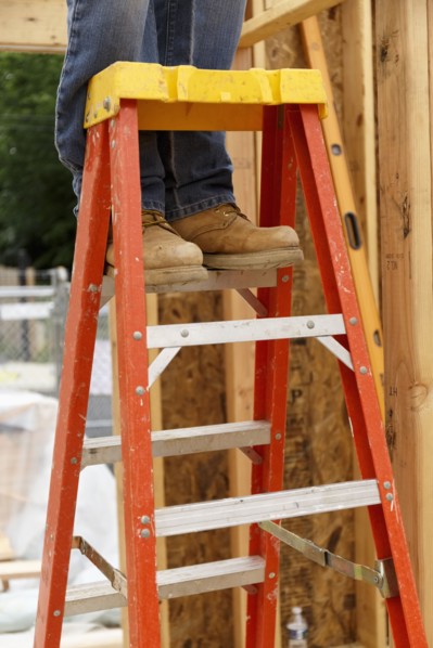 Legs of Caucasian man standing on ladder at construction site