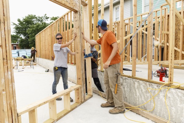 Volunteers holding framed wall at construction site