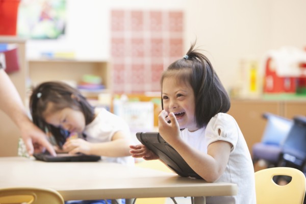 Mixed race Down syndrome student using tablet computer in classroom