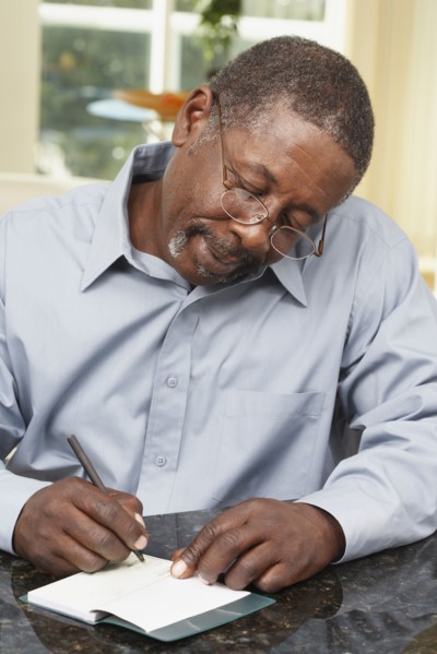 Senior African American man writing check
