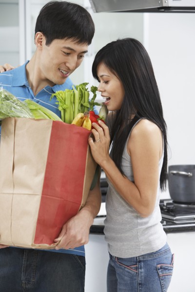 Asian couple looking in grocery bag in kitchen