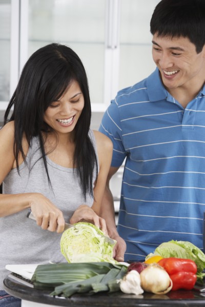 Asian couple chopping vegetables in kitchen