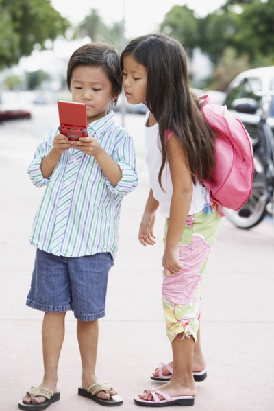 Asian brother and sister playing with handheld game