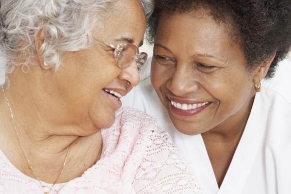 African American mother and adult daughter smiling at each other