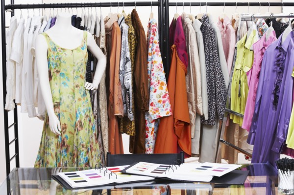 Textile swatches and mannequin in front of clothing rack