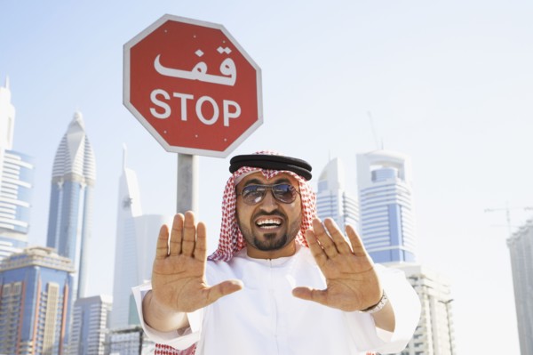 Arab man standing below stop sign