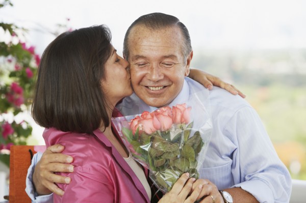Hispanic man giving wife flowers