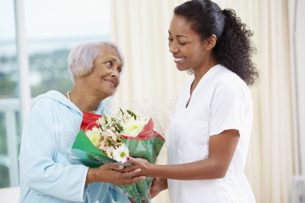 African American woman giving nurse bouquet of flowers