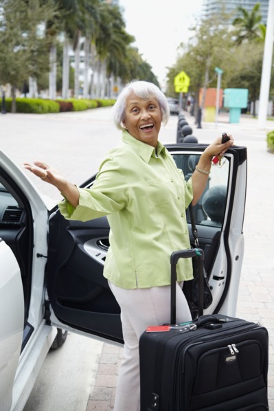 Senior African American woman standing with car and luggage