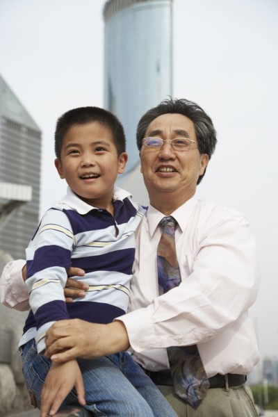 Chinese grandfather and grandson sitting together outdoors
