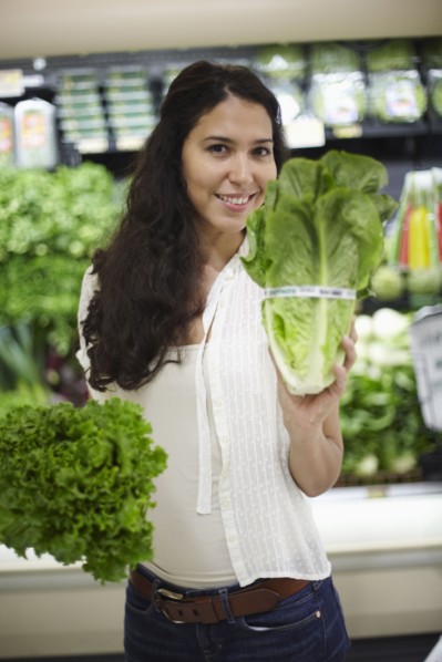 Hispanic woman holding lettuce in grocery store