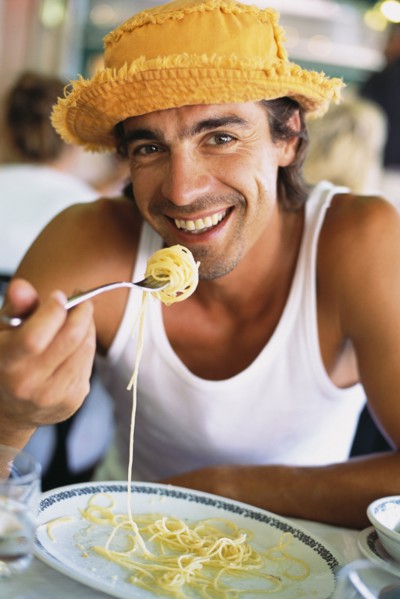 Man eating pasta at sidewalk cafe