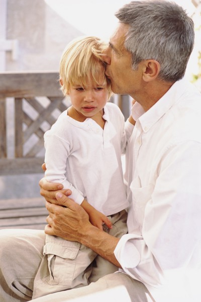 Caucasian father kissing crying son outdoors
