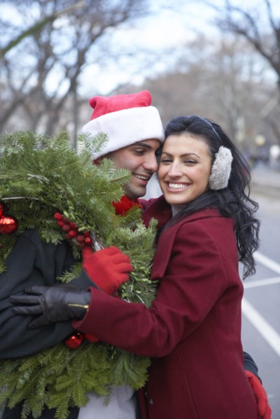 Couple carrying Christmas wreath on city street