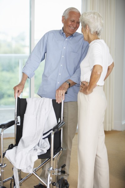 Senior couple standing by wheelchair