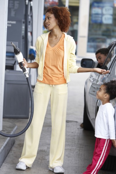 Black mother using pump at gas station