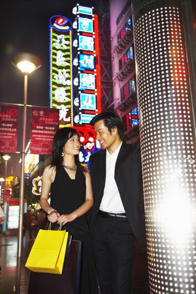 Couple on city street lit up at night