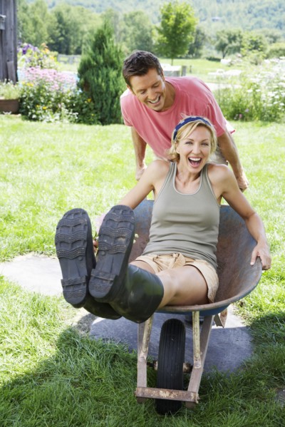 Man pushing girlfriend in wheelbarrow