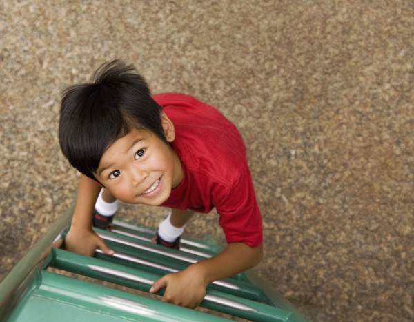 Asian boy climbing ladder on playground