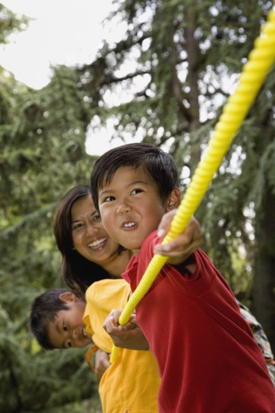 Asian mother and sons playing tug-of-war