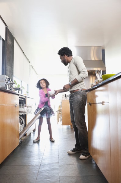 Father and daughter loading dishwasher