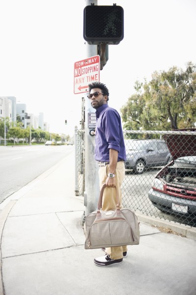 African American man carrying bag on sidewalk