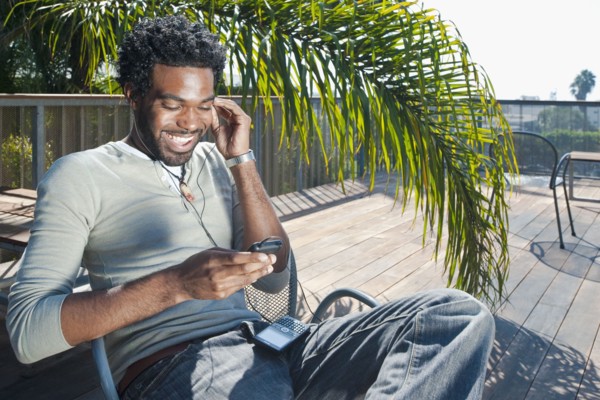 Black man listening to mp3 player on patio