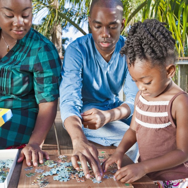 Black father and mother solving puzzle with child