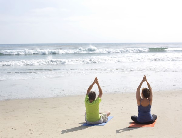 Caucasian couple meditating on beach