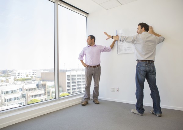 Hispanic businessmen examining blueprints in office